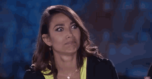 a woman is making a funny face while sitting in front of a dark background .
