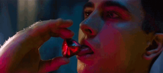 a man is holding a red object in his hand and his eyes are glowing red .