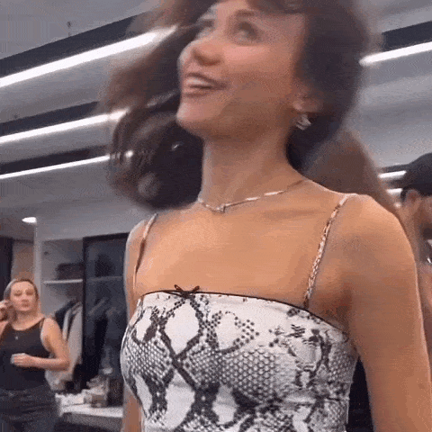 a woman in a snake print top is standing in a room with other women .