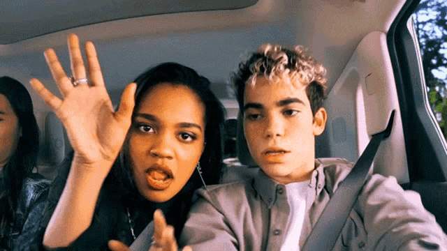 a man and a woman are in a car with their hands up