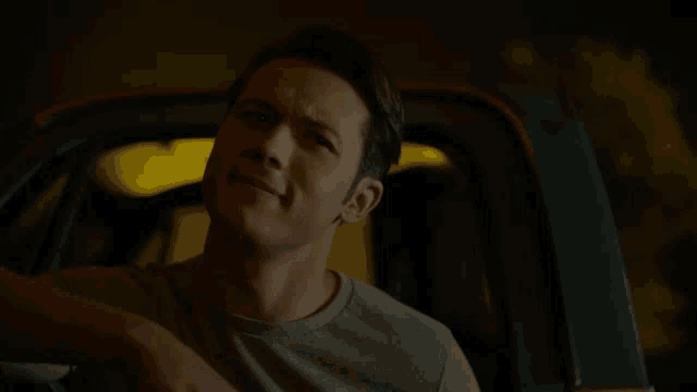 a man in a gray shirt is sitting in the back of a truck
