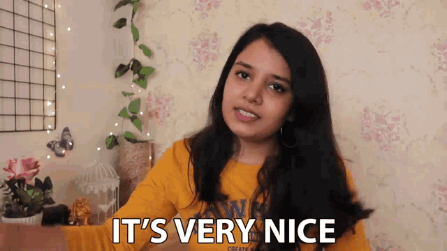 a woman says it 's very nice in front of a wall with flowers