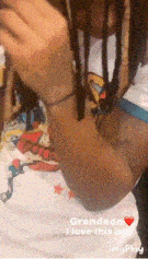a person with dreadlocks is wearing a white shirt that says grandson i love this boy