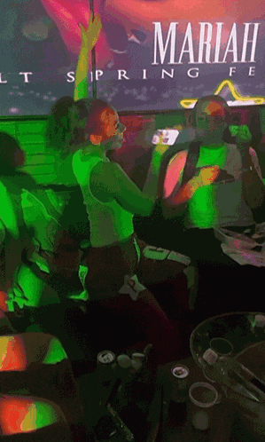 a group of people are gathered in front of a mariah carey poster