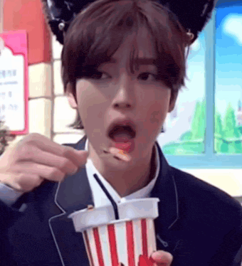 a young man in a suit is eating popcorn with a spoon .