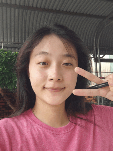 a girl in a pink shirt is making a peace sign