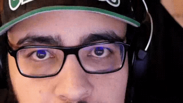a close up of a man wearing glasses and a hat with the letter c on it