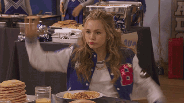 a girl wearing a blue jacket with a letter b on it