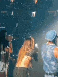 a man in a blue hat is standing next to a woman in a crop top at a party .