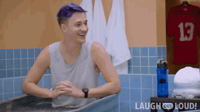 a man with purple hair is sitting in a bathtub with laugh out loud written on the bottom right