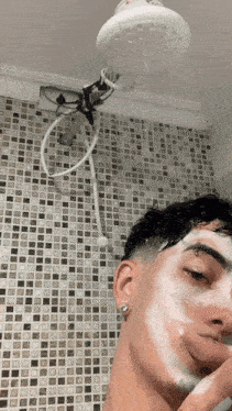 a man is taking a shower with a shower head that is hanging from the ceiling