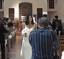 a man is taking a picture of a bride walking down the aisle of a church .