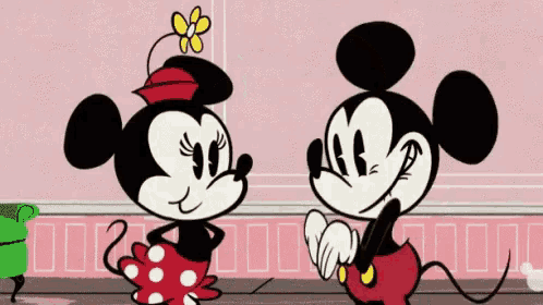 mickey mouse and minnie mouse are standing next to each other on a pink wall .