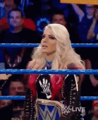a woman is sitting in a wrestling ring holding a wrestling championship belt .