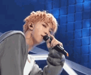 a young man is singing into a microphone while wearing headphones .