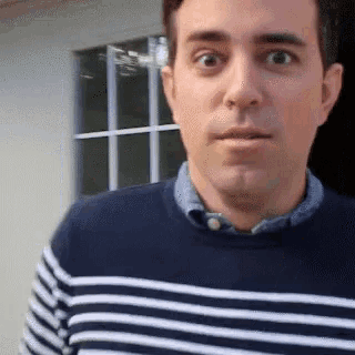 a man wearing a blue and white striped sweater is looking at the camera