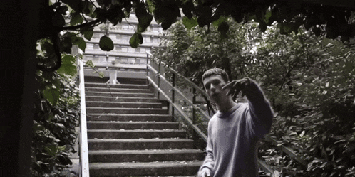a man is standing on a set of stairs in a park with a building in the background