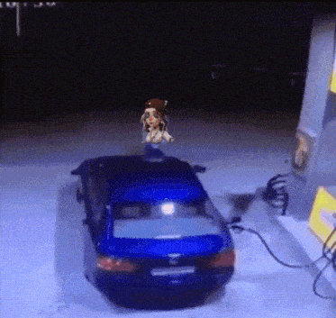 a blue car is being charged at a gas station with a cartoon character on top of it