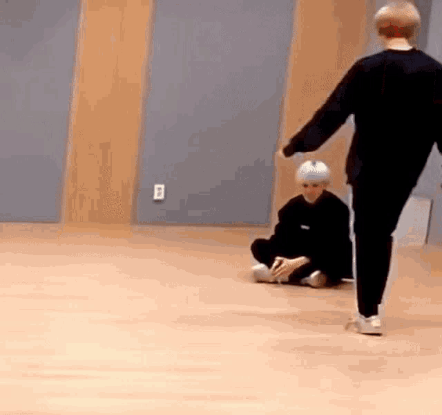 a man is walking towards a boy sitting on the floor .