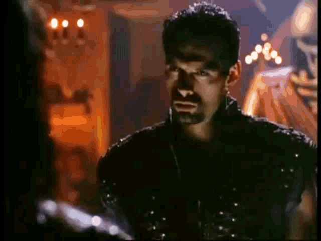 a man with a beard wearing a black leather jacket is talking to another man .