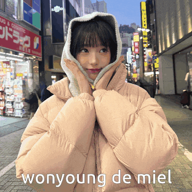 a woman wearing a hooded jacket has wonyoung de miel written on the bottom right