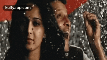 a man and a woman are standing next to each other in the rain holding an umbrella .