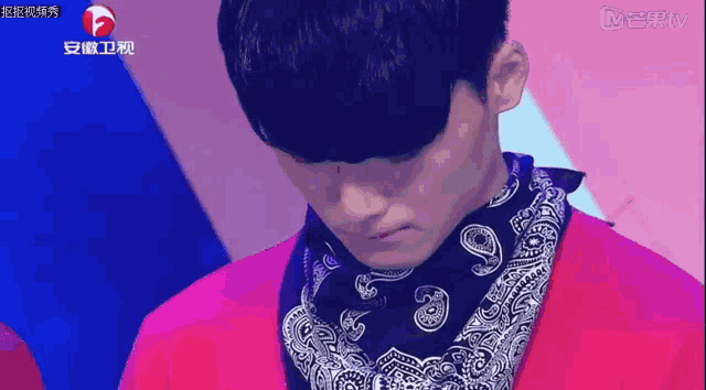 a man wearing a pink jacket and a black bandana is on a tv screen
