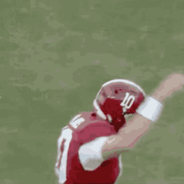 a football player wearing a red uniform and a helmet is running on a field .