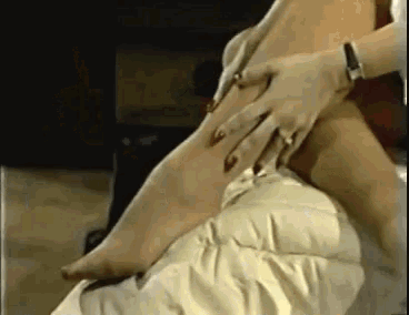 a woman is sitting on a couch with her legs crossed and touching her foot .