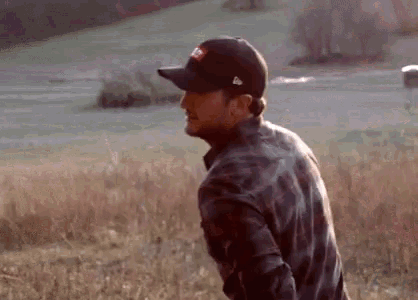 a man wearing a baseball cap is standing in a field .