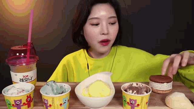 a woman in a yellow shirt is eating ice cream and a drink