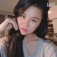 a woman with long hair is taking a selfie with her hand on her chin .