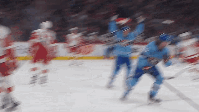 a blurry image of a hockey game with players in blue jerseys