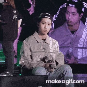 a man in a baseball cap is sitting in front of an lg monitor holding a microphone .