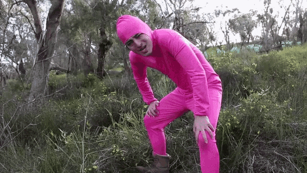 a man in a pink jumpsuit is kneeling down in the grass