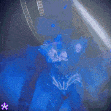 a woman in a bikini is dancing in a dark room with a blue background