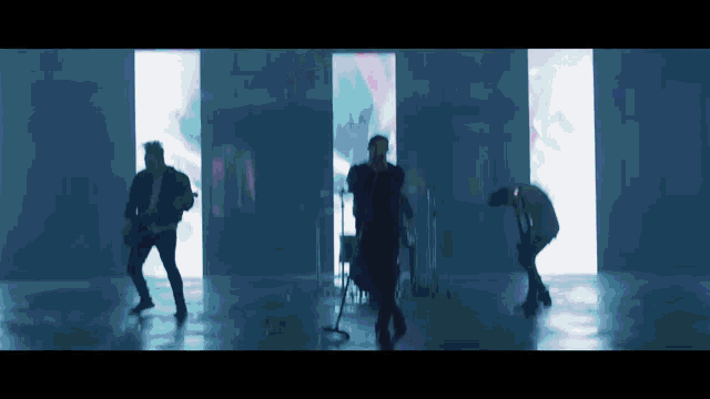 a group of men are standing in front of a microphone in a dark room .