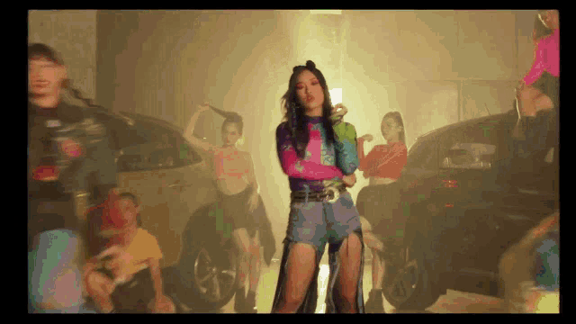 a woman in a colorful outfit is dancing in front of a group of people