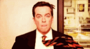 a man in a suit and tie is holding his tie over his head