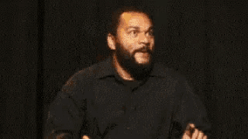 a man with a beard is sitting next to a guitar