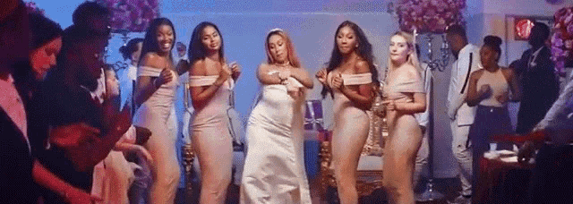 a bride and her bridesmaids are dancing in front of a crowd of people at a wedding reception .