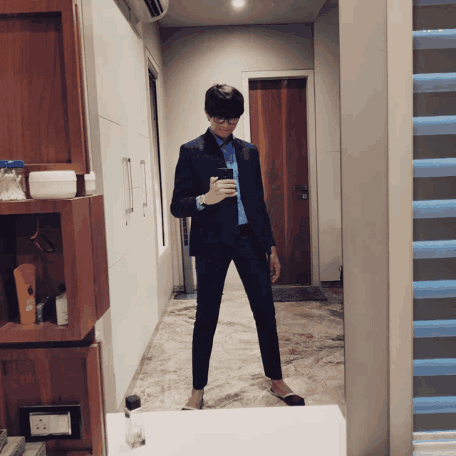 a man in a suit taking a picture of himself in a mirror