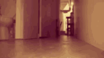 a silhouette of a person walking down a hallway in a dark room .
