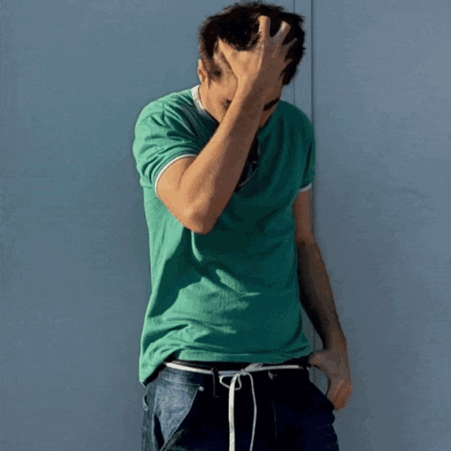 a young man wearing a green t-shirt and sunglasses looks at the camera
