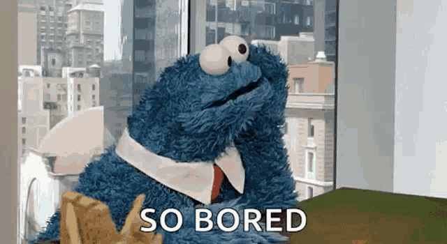 cookie monster from sesame street is sitting at a table with chips and says so bored .