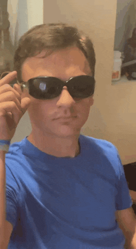 a man wearing a blue shirt and black sunglasses