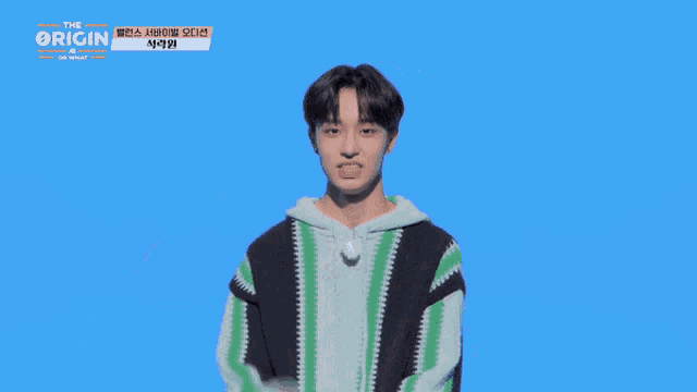 a young man in a green and black striped sweater is pointing