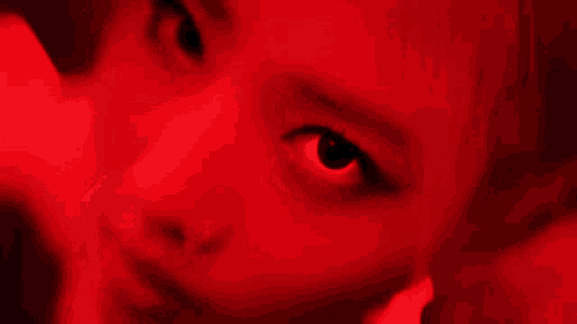 a close up of a woman 's face with red lights behind her .