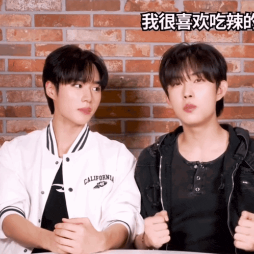 two young men are sitting next to each other with one wearing a jacket that says california