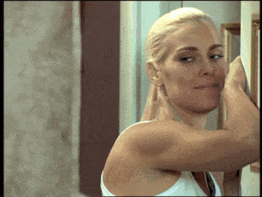 a woman in a white tank top is standing in front of a door